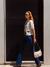 a lady wears a dark wash jeans with a white knitted top